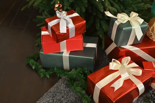 Beautiful gift boxes on floor near decorated Christmas tree. Winter holiday celebration concept.