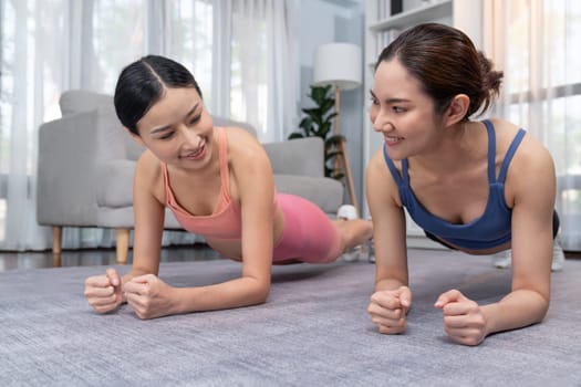 Fit young asian woman planing on the living room floor with her trainer or exercise buddy. Healthy lifestyle workout training routine at home. Balance and endurance exercising concept. Vigorous