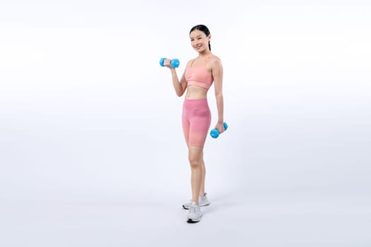 Vigorous energetic woman doing dumbbell weight lifting exercise on isolated background. Young athletic asian woman strength and endurance training session as body workout routine.