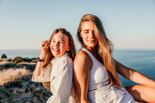 Close up portrait of mom and her teenage daughter hugging and smiling together over sunset sea view. Beautiful woman relaxing with her child.