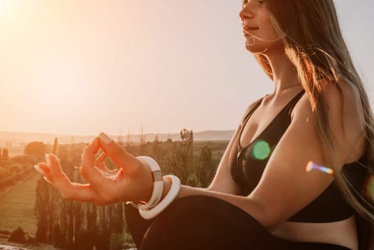 Well looking middle aged woman with long hair, fitness instructor in leggings and tops doing stretching and pilates on the rock near forest. Female fitness yoga routine concept. Healthy lifestyle.