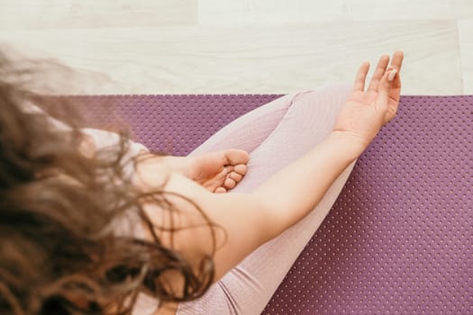 Young woman with long hair in white swimsuit and boho style braclets practicing outdoors on yoga mat by the sea on a sunset. Women's yoga fitness routine. Healthy lifestyle, harmony and meditation