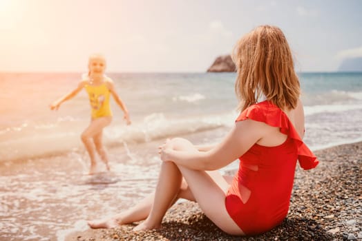 Happy loving family mother and daughter having fun together on the beach. Mum playing with her kid in holiday vacation next to the ocean - Family lifestyle and love concept.