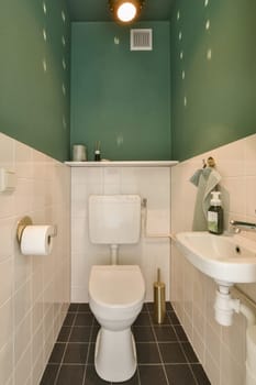 a bathroom with green walls and white tiles on the floor, along with a toilet in the corner of the room