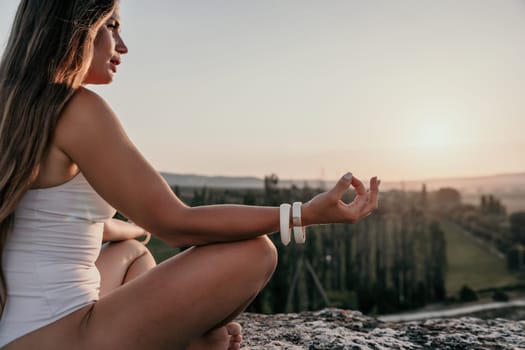 Young woman with black hair, fitness instructor in pink sports leggings and tops, doing pilates on yoga mat with magic pilates ring by the sea on the beach. Female fitness daily yoga concept