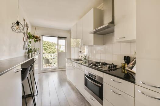 a modern kitchen with white cabinets and black counter tops on the island in front of the sink is next to the window