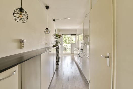 a long narrow kitchen with white cabinets and black counter tops on either side by the door to the dining room