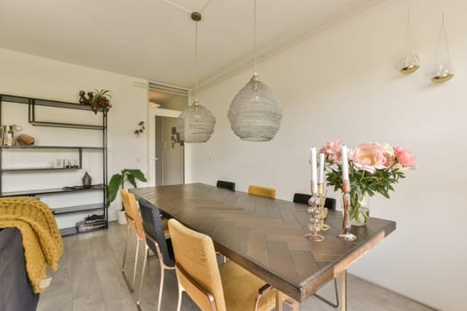 a dining room with flowers in vases on the table next to the couch and shelves for storage behind it