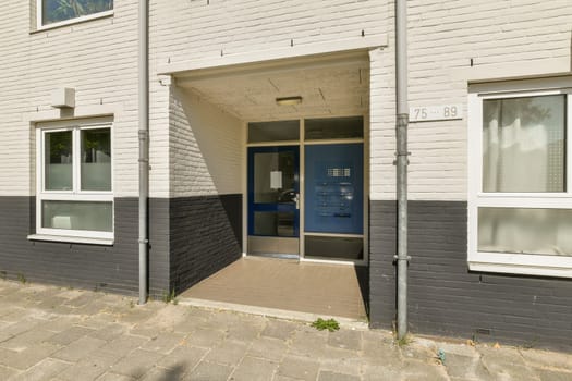 a building that is white and grey with black trim on the doors, windows, and side entryways