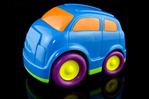 blue plastic car on black background with reflection