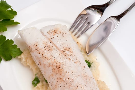 A cod fillet on puree with a fish knife and fork