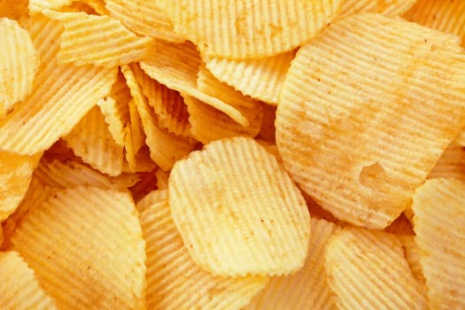 Golden potato chips background, closeup studio shot
