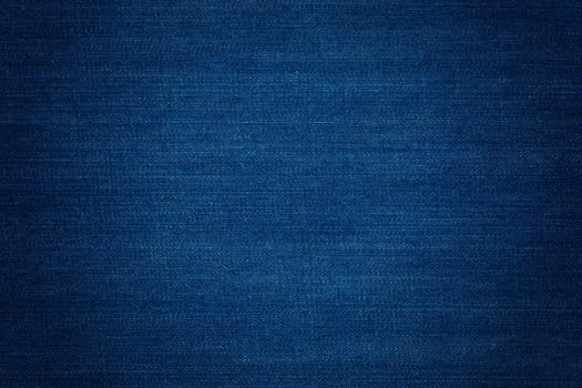 Dark blue denim background, detailed texture with vignette