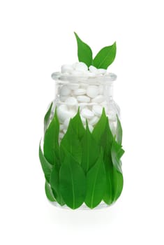 Herbal supplement pills and fresh leaves in glass - alternative medicine concept