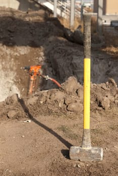 yellow sleg hammer on construction site with a jack hammer in the background