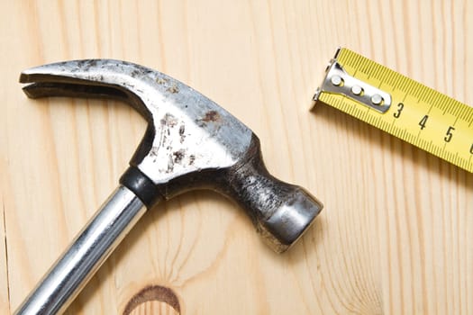Old hammer and tape messure  on wood background