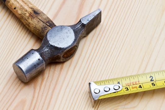 Old hammer and tape measure on wood background