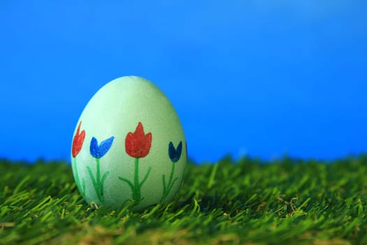 Easter decoration made of single,colorfully painted,Easter egg in green artificial grass