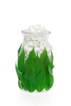 Herbal supplement pills in pill bottle with fresh leaves - alternative medicine concept