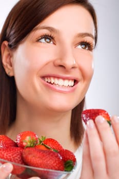 Beautiful brunette girl eating a strawberry close up
