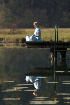 young girl relaxing on pier in early morning