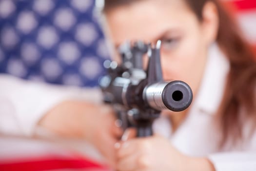 woman aiming with machine gun over american flag - focus on gun barrel