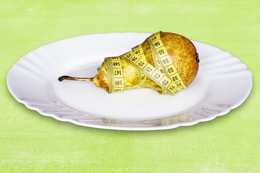 healthy pear with measure tape,in a plate