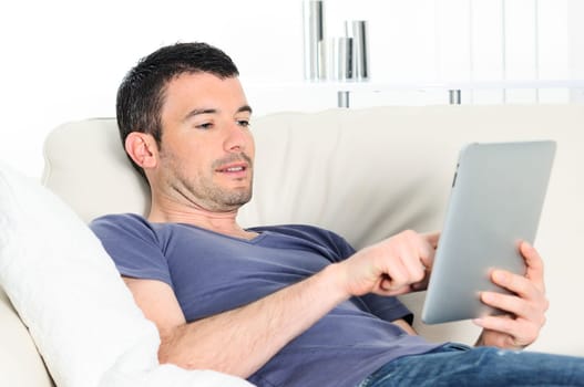 attractive relaxed and positive man is surfing on his tablet