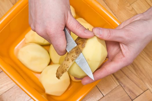 woman&#039 s hands peeling potatoes with a knife
