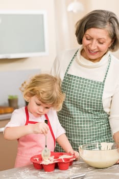 Woman and little girl make cupcakes together fill baking form