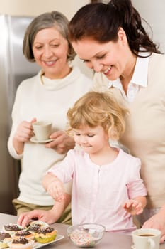 Mother and daughter decorating cupcakes sprinkles happy together at home