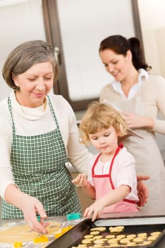 Little girl with grandmother baking cookies put on tray