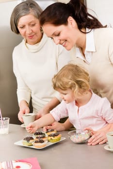 Mother and daughter decorating cupcakes sprinkles happy together at home