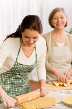 Happy woman making dough for apple pie grandmother drink wine