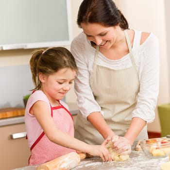 Mother and daughter prepare dough baking apple cake happy together