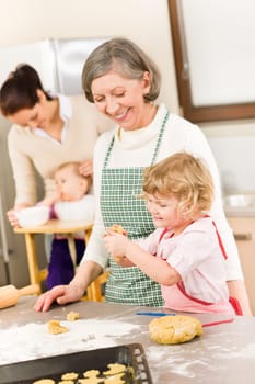 Grandmother with little girl prepare dough for baking in kitchen