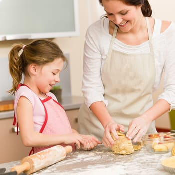 Mother and daughter prepare dough baking apple cake happy together