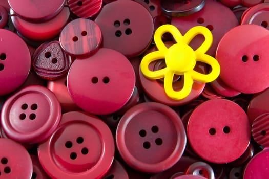 A yellow flower shaped button sitting on top of a background of red buttons