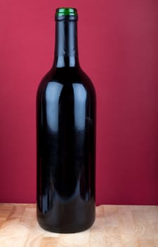 Wine bottle on wooden plate against red background