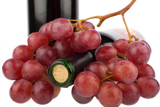 Wine bottle lies between grapes
