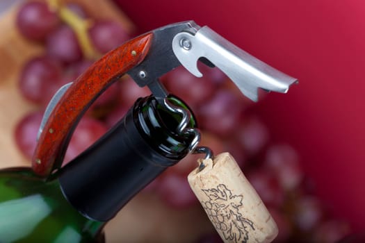 Corkscrew with cork lying on the neck of a wine bottle