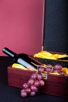 Wine bottle in decorative gift box decorated with grapes