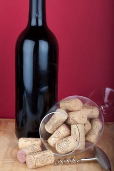 Glass with wine cork lying in front of a wine bottle