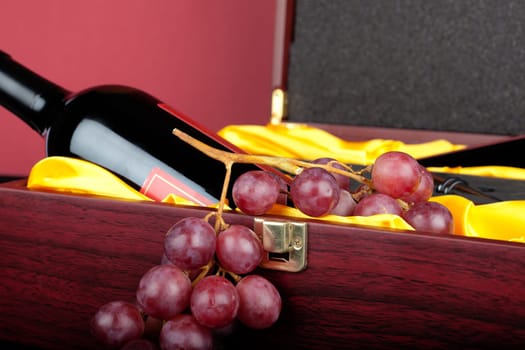 Wine bottle in decorative gift box decorated with grapes