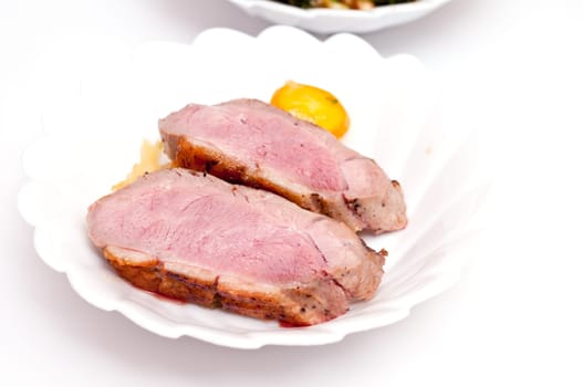 Two slices of pink roasted duck breast with kumquat