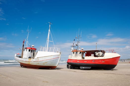 Worn boats on the beach towards blue sky