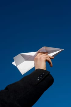 Hand holding a Paper Airplane towards blue sky