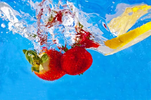 Fresh fruits falling into the water on a blue mosaic background