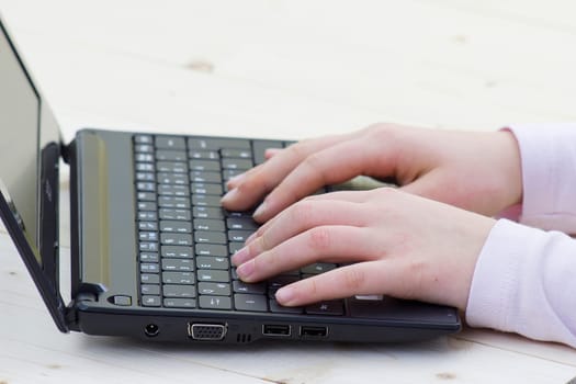 child hands typing on a keyboard of laptop