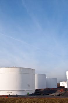 white tanks in tank farm with blue sky